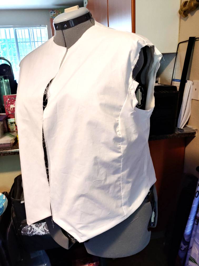 The body of a white shirt finished only on the bottom hem, sitting on a gray dress form