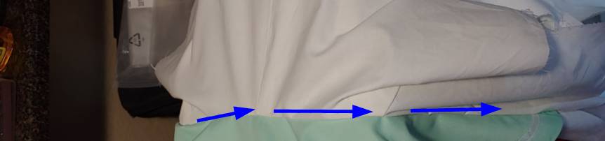 Stitch just underneath the collar along the shirt to secure the raw edge. Location shown with blue arrows.