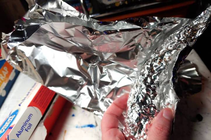 Wrapping the horn like a burrito. The crushed foil horn is on the right side, sitting partially wrapped in a sheet of foil