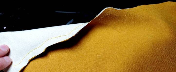 Irregular hem sewn with the excess fabric trimmed. Left side is flipped down to show the stitches along the lining