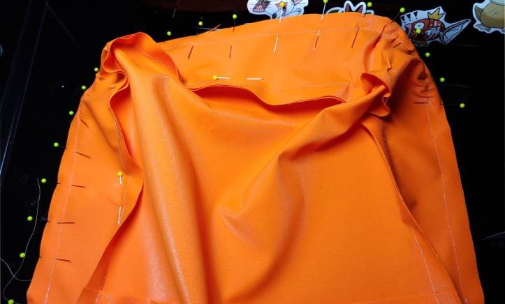 Sewing the front body piece to the gusset. Pins surround the border, holding the fabric together. A few pins scattered on the body keep the fabric from getting in the way while sewing.