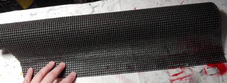 Black shelf liner roll partially unrolled. There's a section cut out the side from other projects