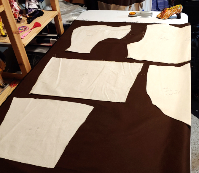 Muslin pattern pieces laid out on brown suede