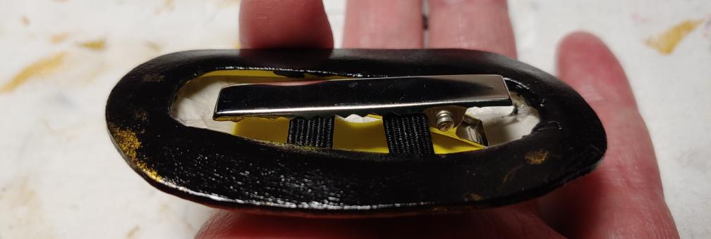 Alligator fully inserted in the hair clip (which is being held upside down). The flat side is facing up here