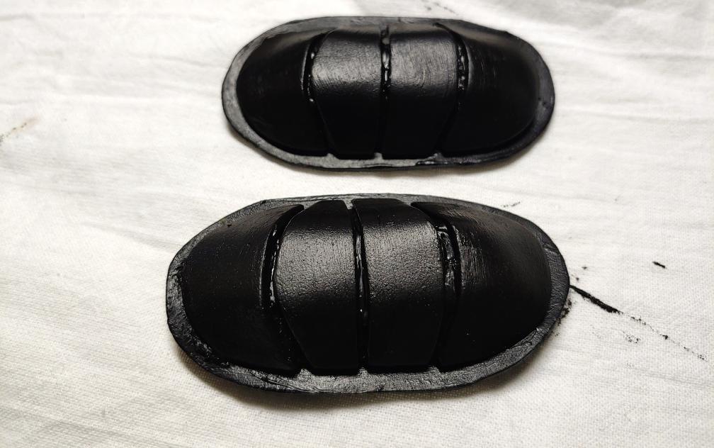 two clips, both right-side up, painted completely black and sitting on a white cloth