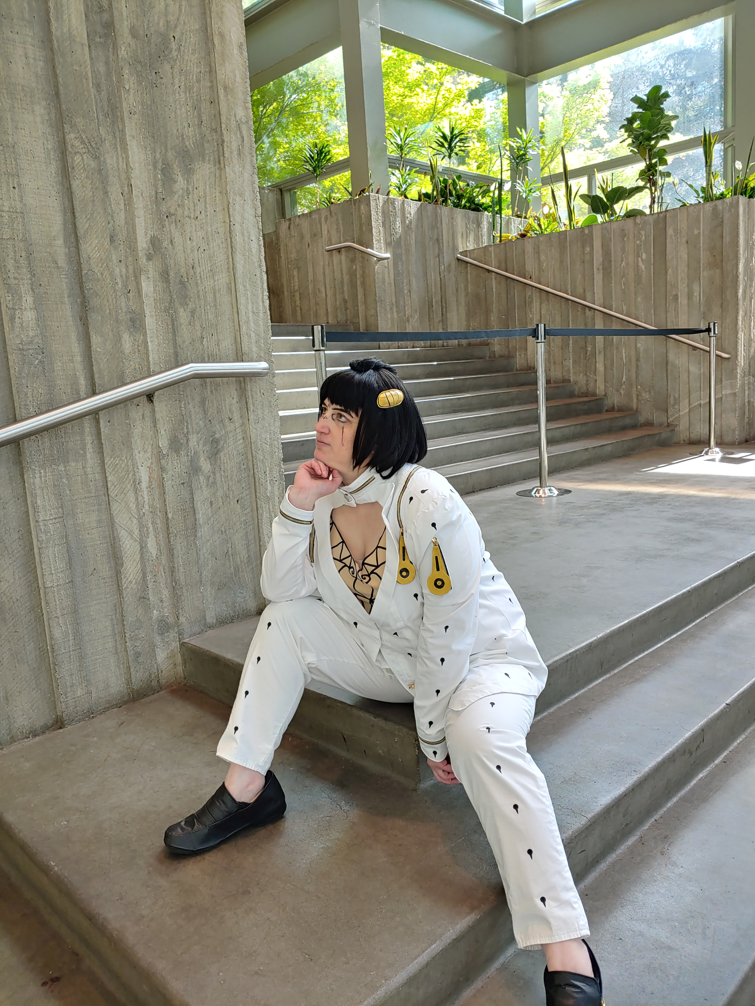 Bruno sitting on stairs with green planters and bright windows in the back, waiting for someone.