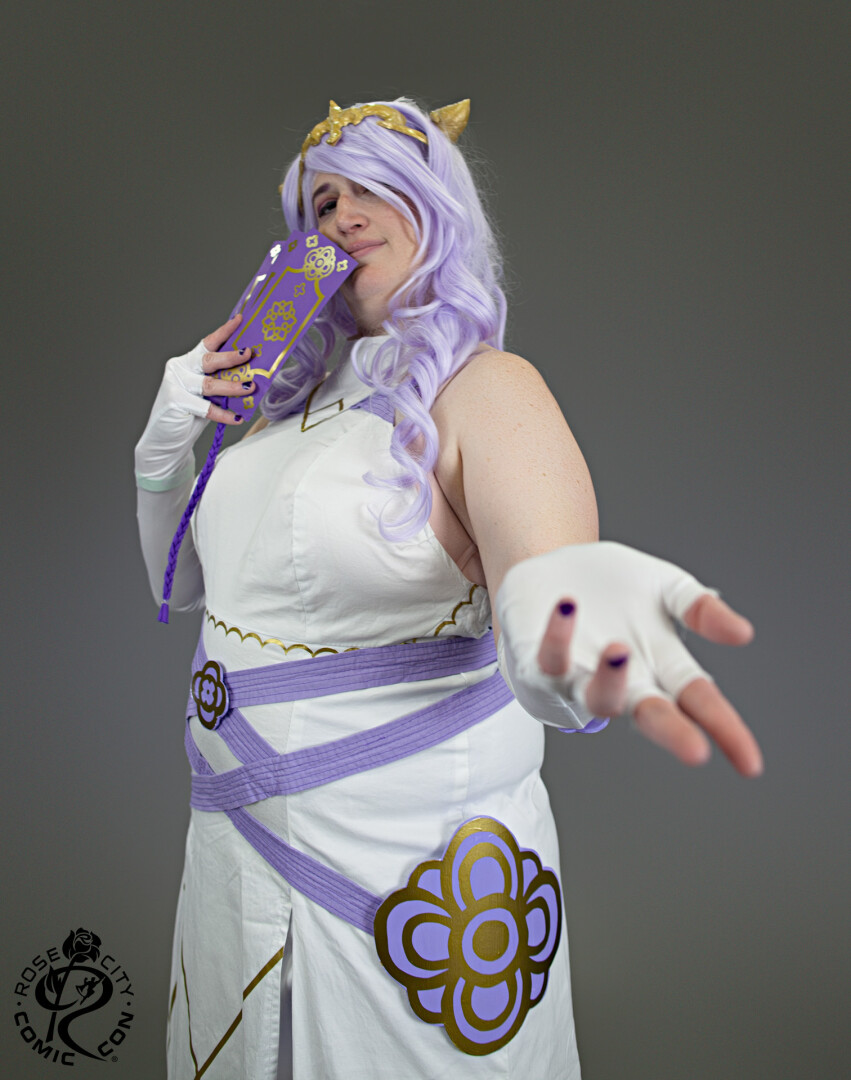 Camilla with her hand outstretched, taken with a gray studio background