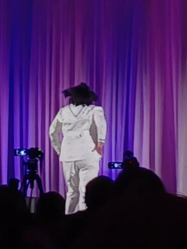 Bucciarati on a stage with a purple curtain facing backwards with fabulous hair flip