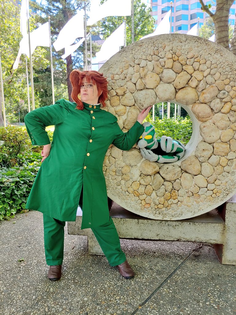 Kakyoin leaning into a stone round artwork with Hierophant Green sitting in the middle of the stone round thing