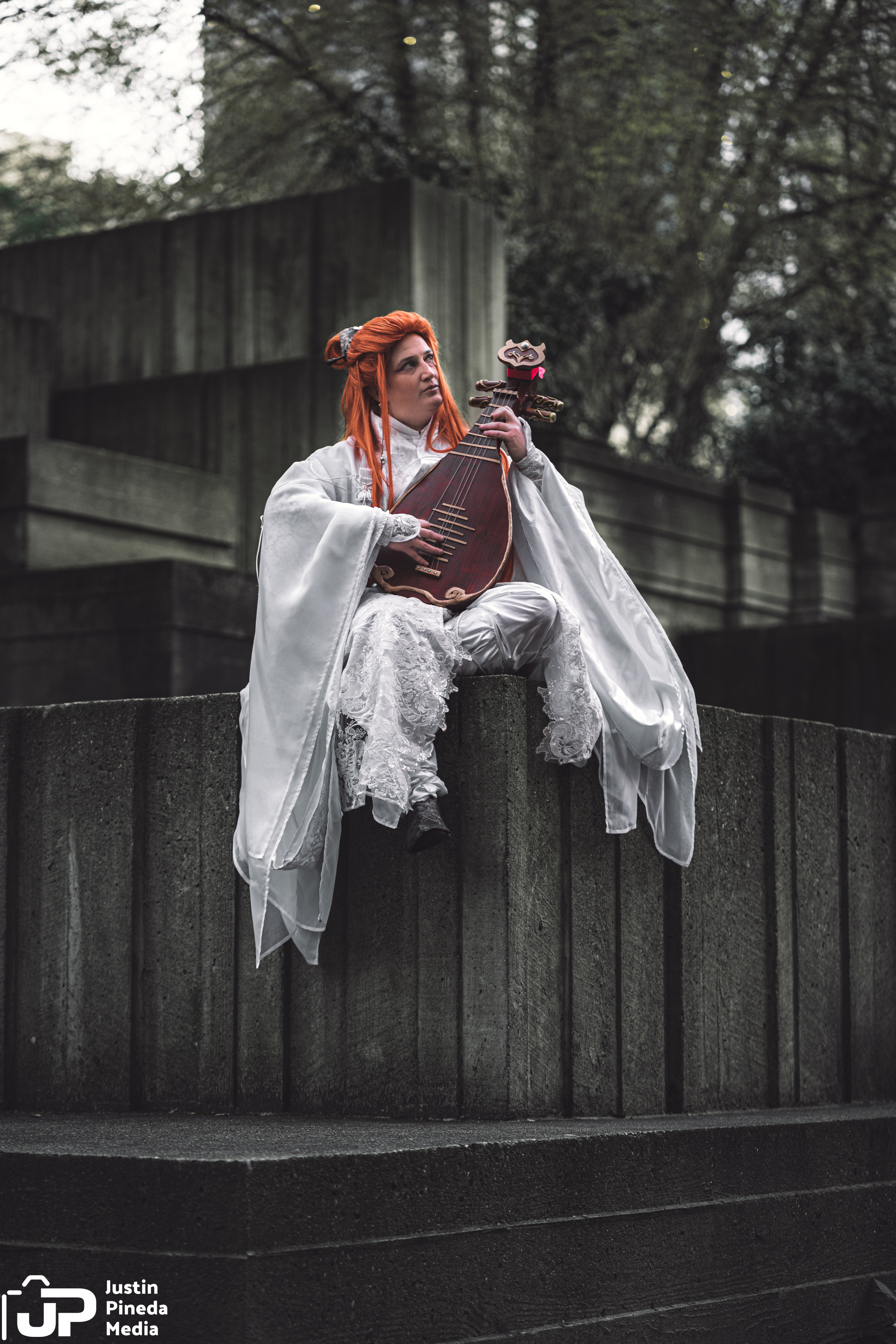 Lang sitting on an architectural fountain, sleeves and robes draped over the edges