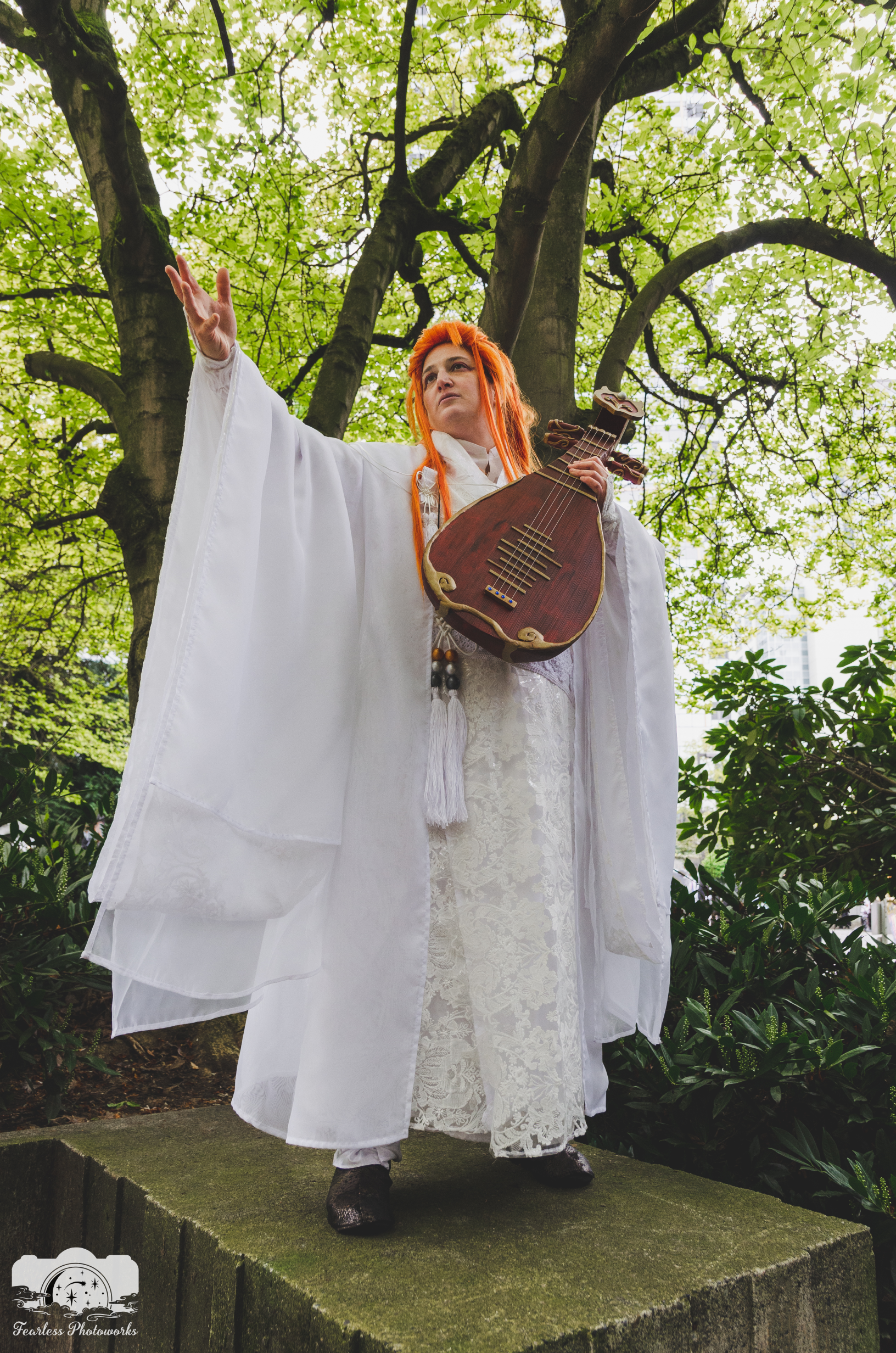 Lang reaching up to the left, standing on a pedestal in a green forest