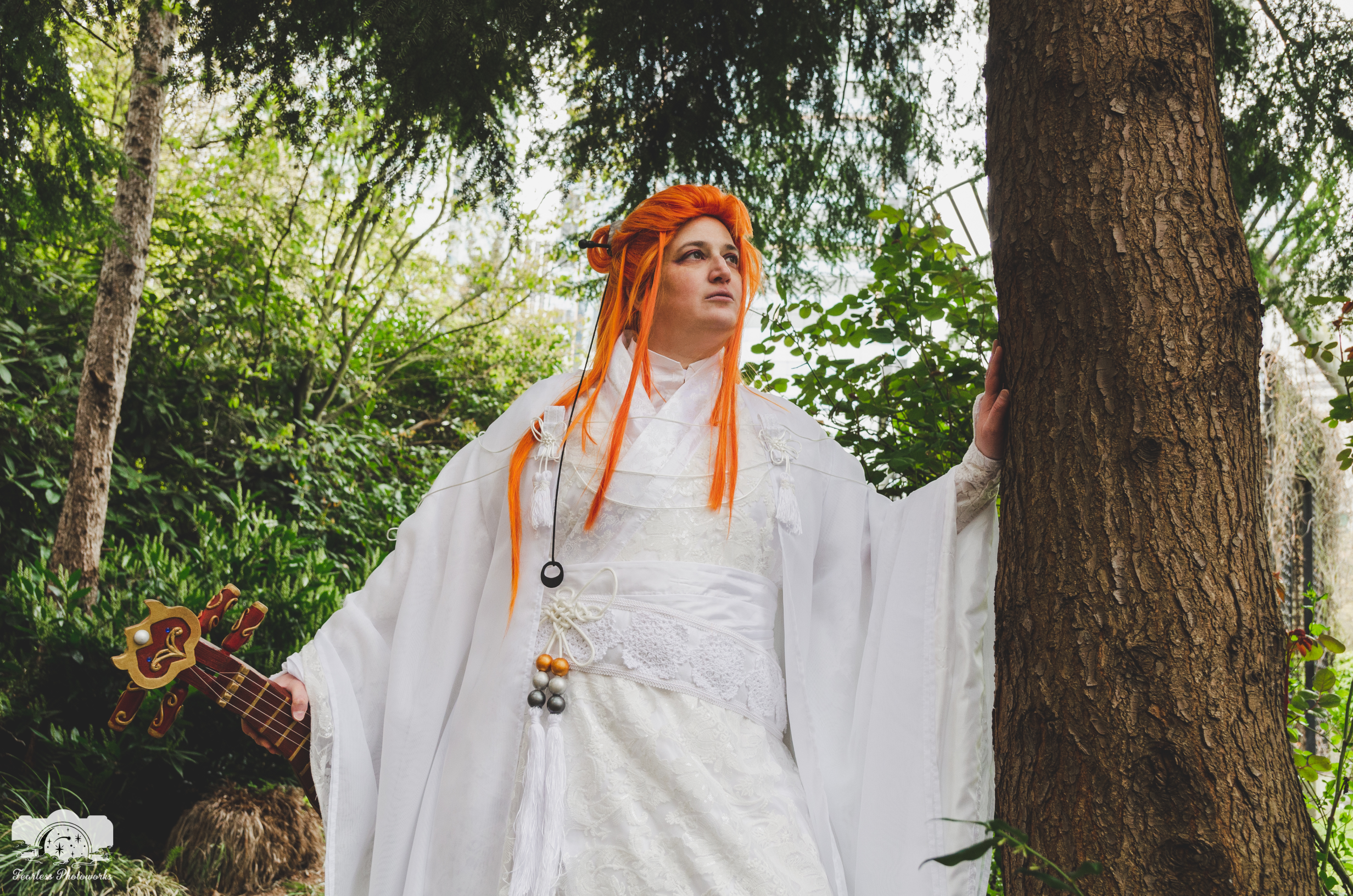 Lang with one hand on a tree, looking forward