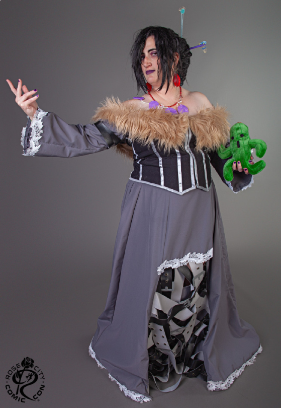 Lulu against a gray background with hand extended to the left, holding a cactuar in the right