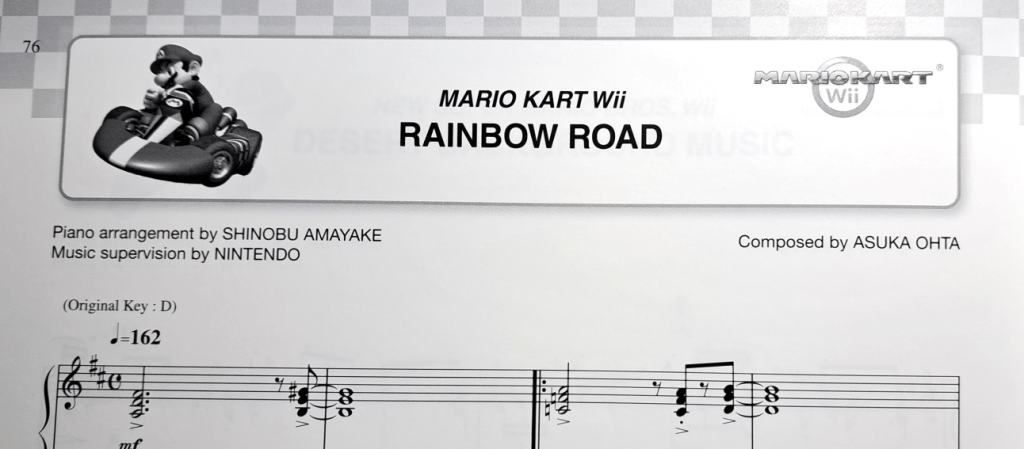 title decorations. Top border is a checkered racing flag. Right of the title is "Mario Kart Wii". To the left of the title is Mario in a go-kart. Title says "Mario Kart Wii Rainbow Road"