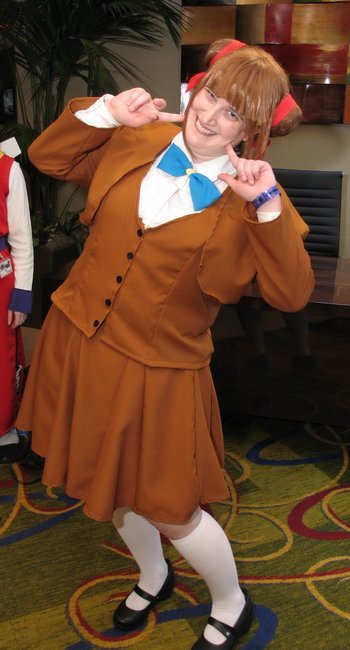 Miaka leaning to the right, fingers on cheeks, trying to look cute