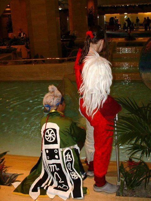 Nooj (right) and Baralai (left) in front of a fountain, backs to camera