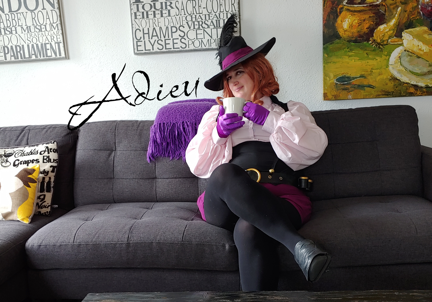 Noir sitting on a black couch with a teacup with "Adieu"