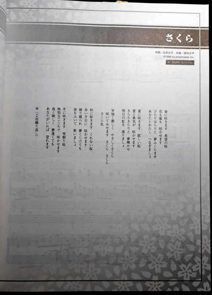 Lyrics page showing the words for the song "Sakura". The lyrics are written in tranditional order: top to bottom, right to left. At the bottom is a cherry blossom design.