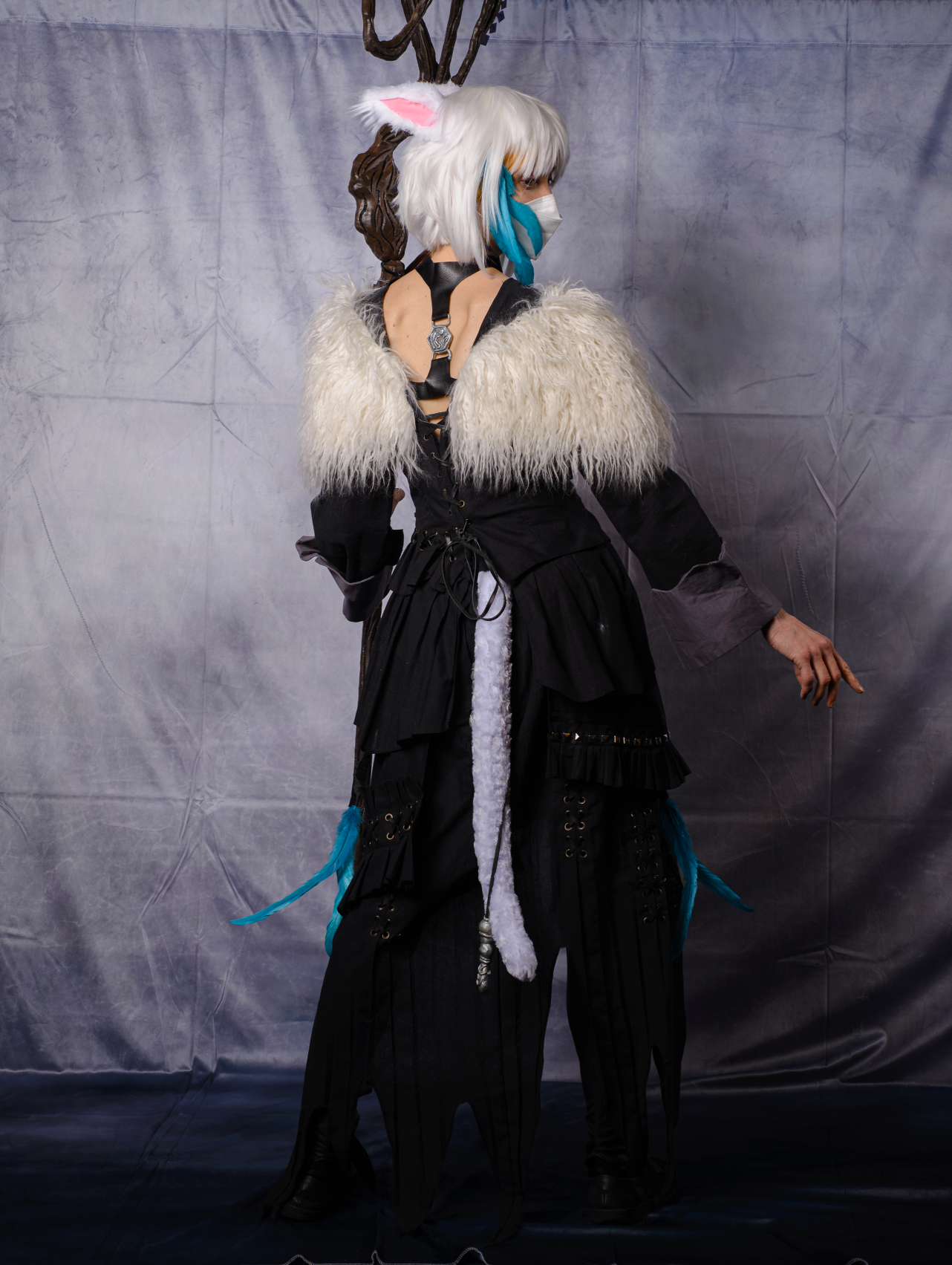 Y'shtola standing in front of a gray curtain, facing backward