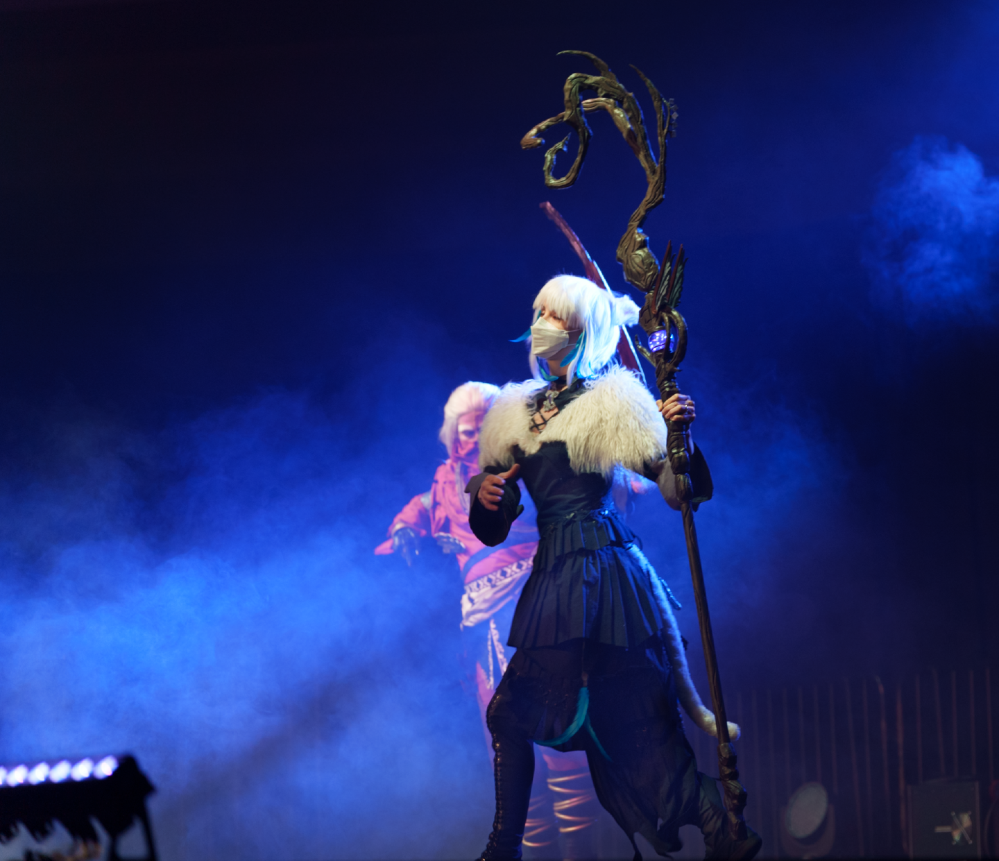 Y'shtola standing on a foggy stage with Ran'jit lurking in the background