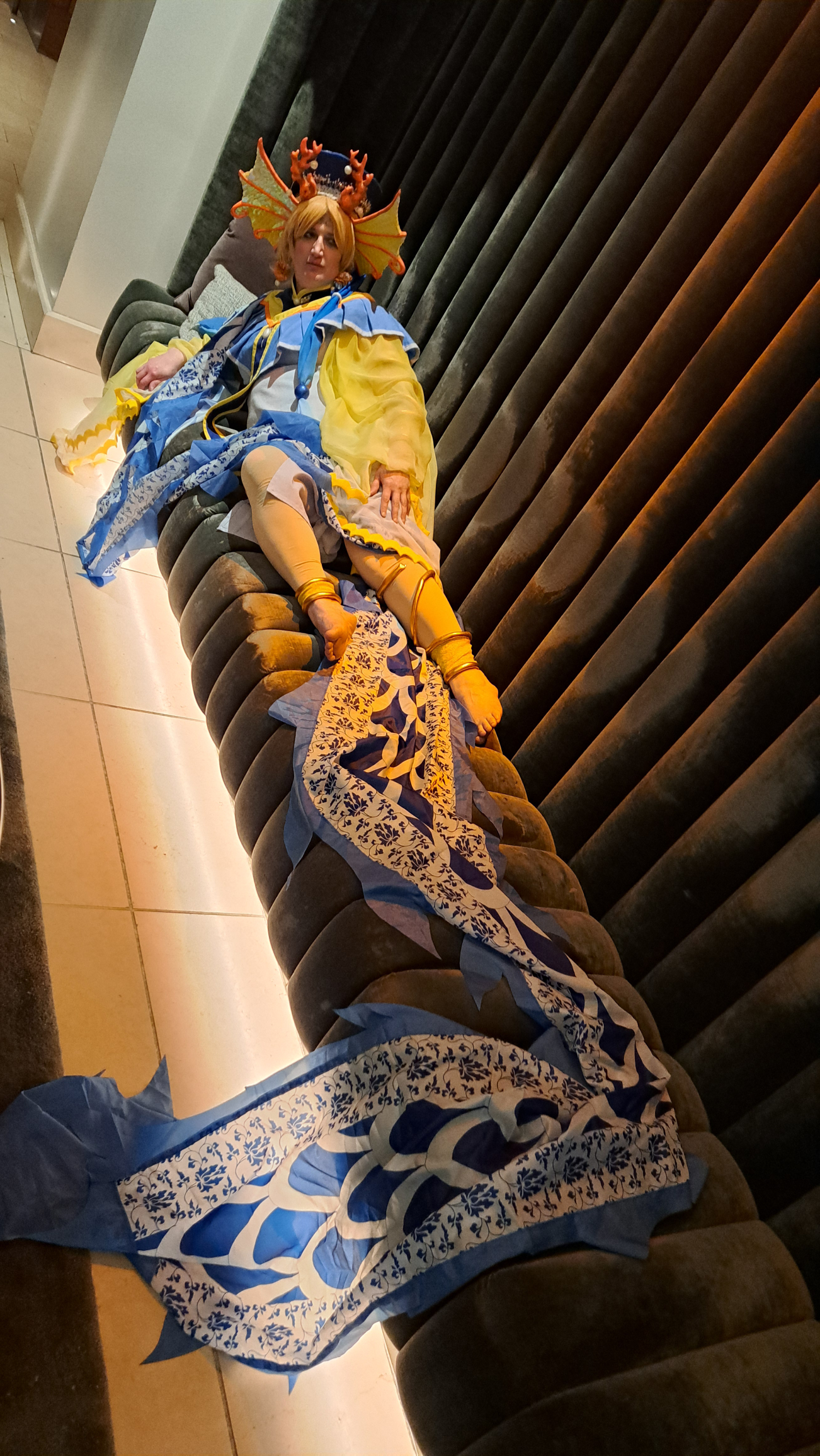 Yui on a long brown couch, wrapped in a dragon