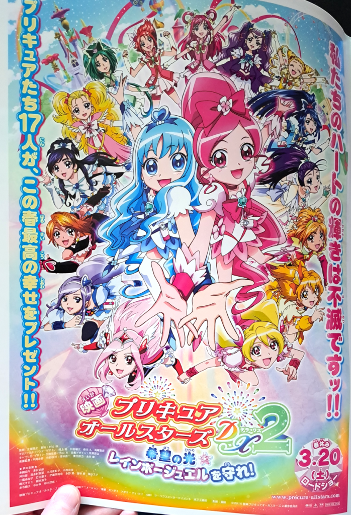the DX2 artwork with Cure Blossom and Cure  Marine in the center with all the other Cures around in a circle.