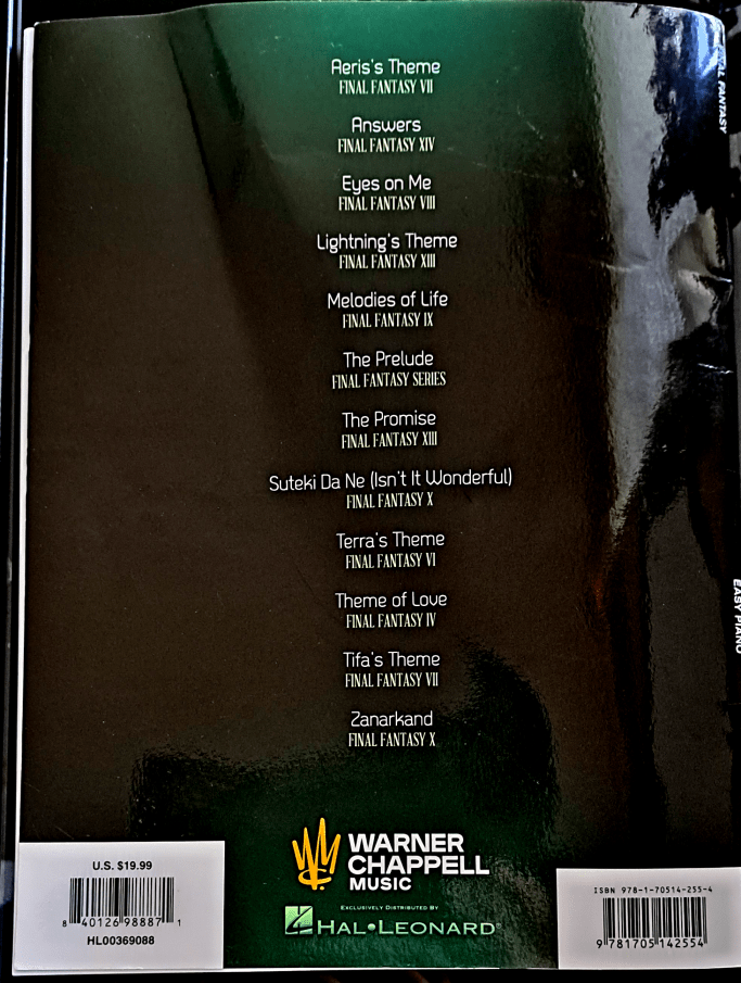 Shiny black back cover reflecting the curtains and flowers above my desk. The back lists the table of contents with names of songs and games listed beneath them. Refer to Song List for full text.