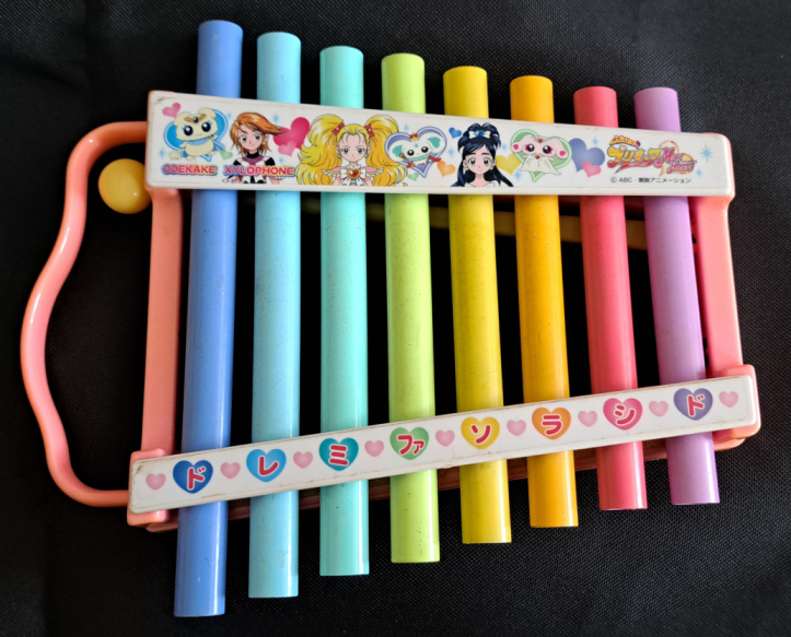Pretty cure Xylophone with different color metal pipes for the keys. Along the top are all the Max Heart characters. Along the bottom are Do Re Mi Fa So La Ti Do in Japanese