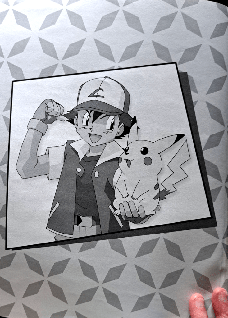 Front piece in the book and the only grayscale artwork. Ash flexes with one arm and holds Pikachu in the other, both looking happily at each other. Background is four diamonds pointing next to each other to make a flower-like shape repeated all over.