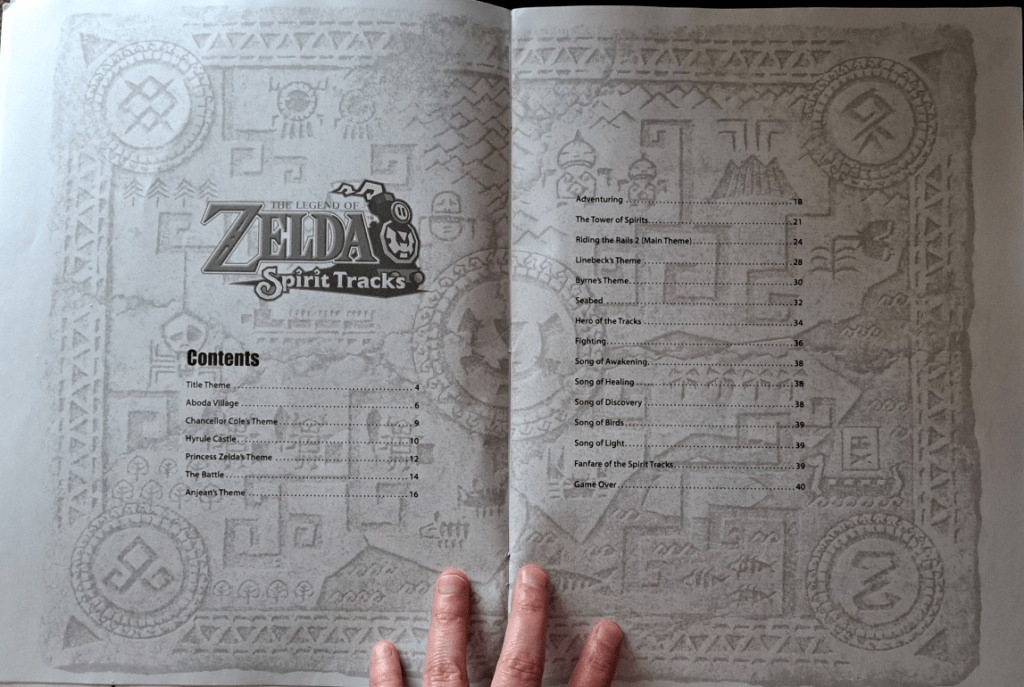 Table of contents with a carved map design in light gray in the background. On the left page is the title "Legend of Zelda Spirit Tracks." Starting on the left page going right is the list of songs with their corresponding page numbers. For the text, refer to Song List section.