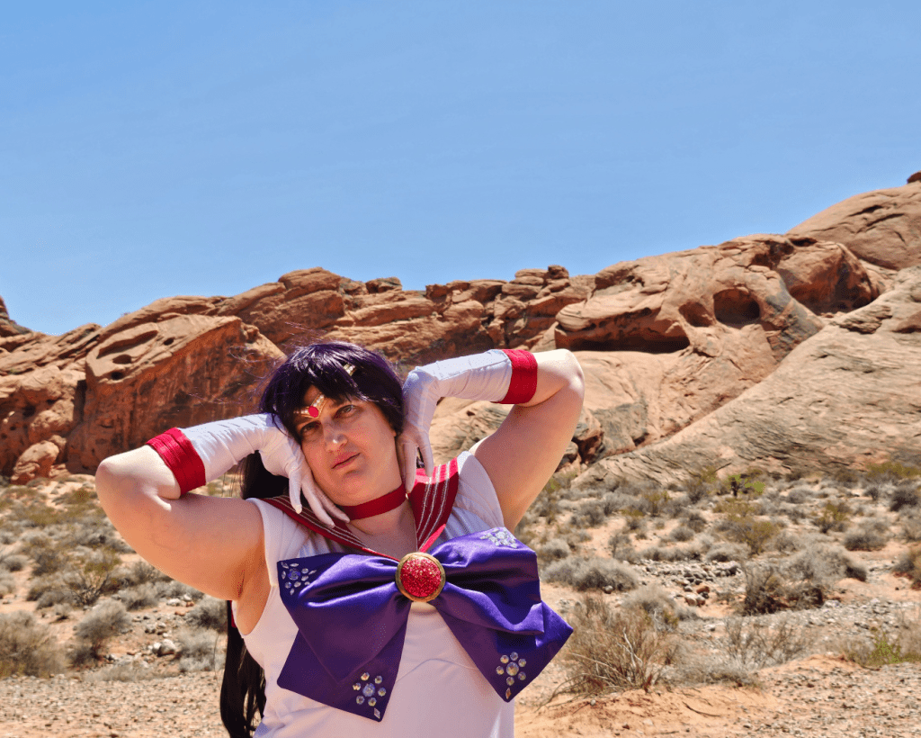 Close up shot of Mars with hands against the side of the face in front of a desert
